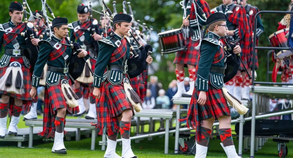 Un gruppo di uomini in kilt scozzese e uniforme suona la cornamusa e i tamburi durante una sfilata alla Dollar Academy.