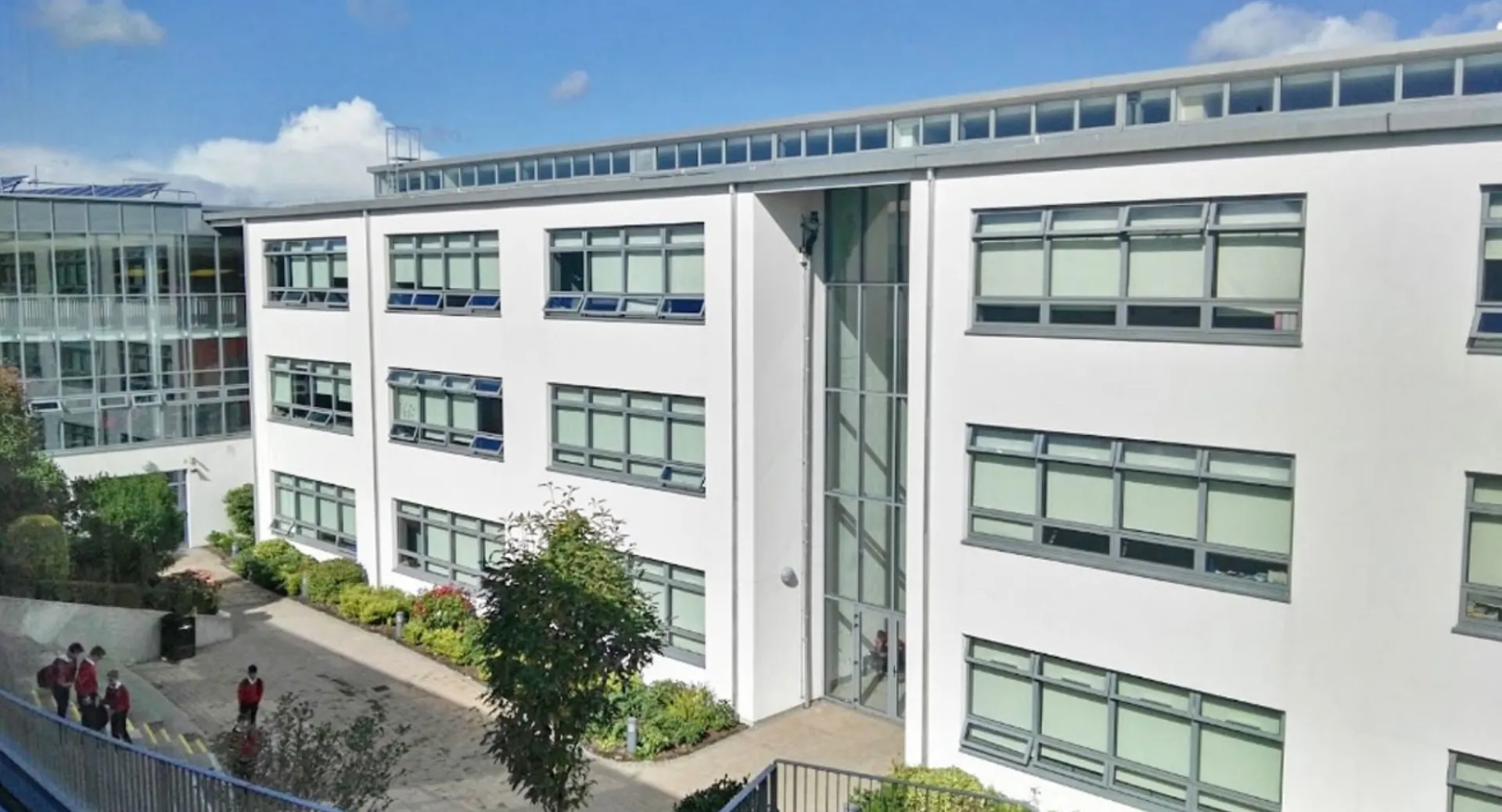 Si vede l'edificio a più piani della Coláiste Chill Mhantáin con facciata in vetro e verde circostante.