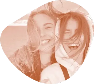 Dos jóvenes riendo juntas al aire libre con el pelo al viento