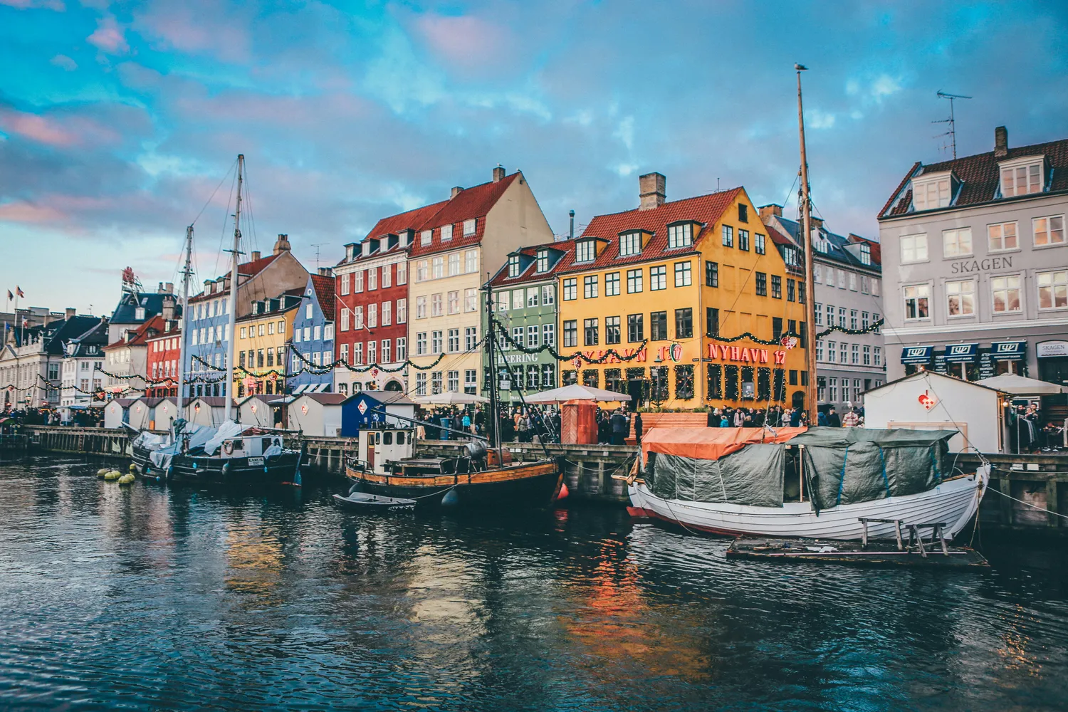 Case colorate e barche ormeggiate lungo il canale di Nyhavn a Copenhagen al tramonto