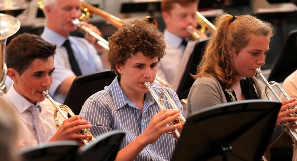 Studenti del King's College suonano diversi strumenti musicali su un palco durante un'esibizione.
