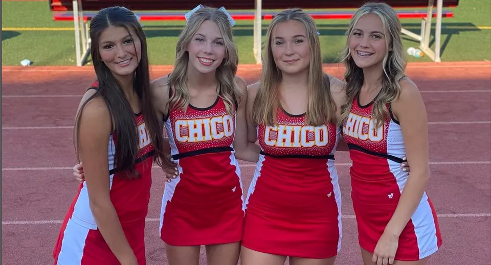 Quattro studentesse in divisa da cheerleader rossa sono sul campo sportivo del Chico Unified School District.