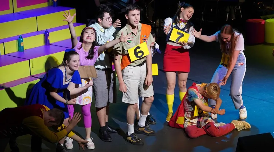 Un gruppo di studenti del Dickson College si raccoglie nel dietro le quinte con una scenografia colorata.