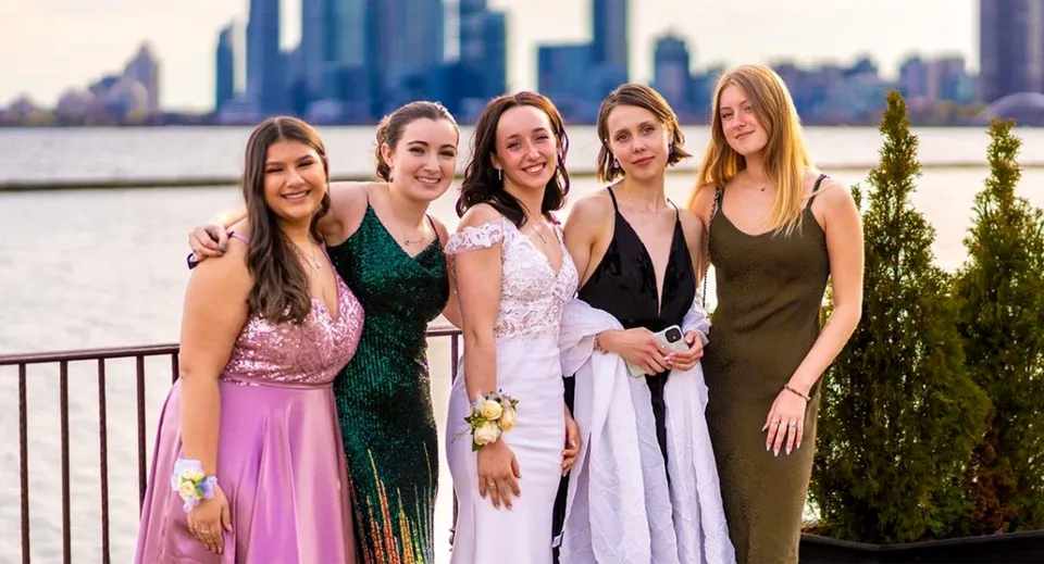 Un gruppo di cinque studentesse della Lawrence Academy posa davanti allo skyline di una città con edifici alti.