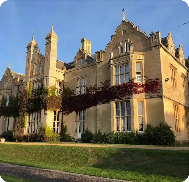 Storico edificio scolastico inglese con torrette ed edera al tramonto
