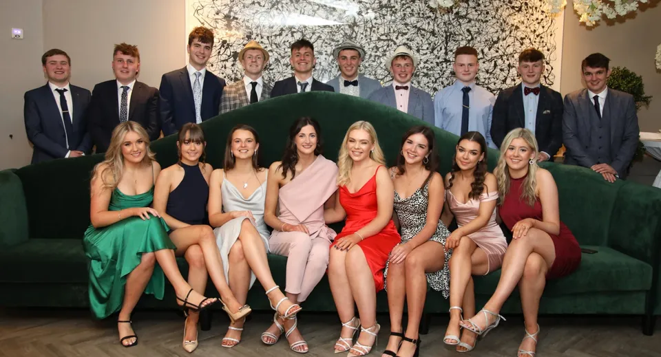 Un gruppo di persone in abito formale si mette in posa davanti a uno sfondo floreale nel campus della Rishworth School.