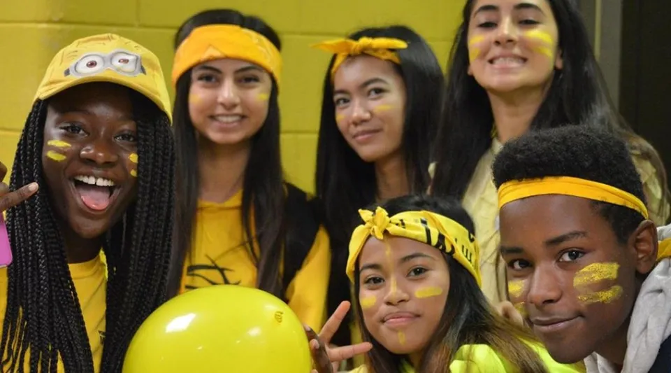 Un gruppo di studenti e studentesse con accessori gialli posa insieme nel campus del Fort Richmond Collegiate.