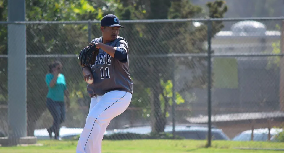 Un giocatore di baseball in divisa blu scuro si trova sul campo da gioco del Duarte Unified School District.
