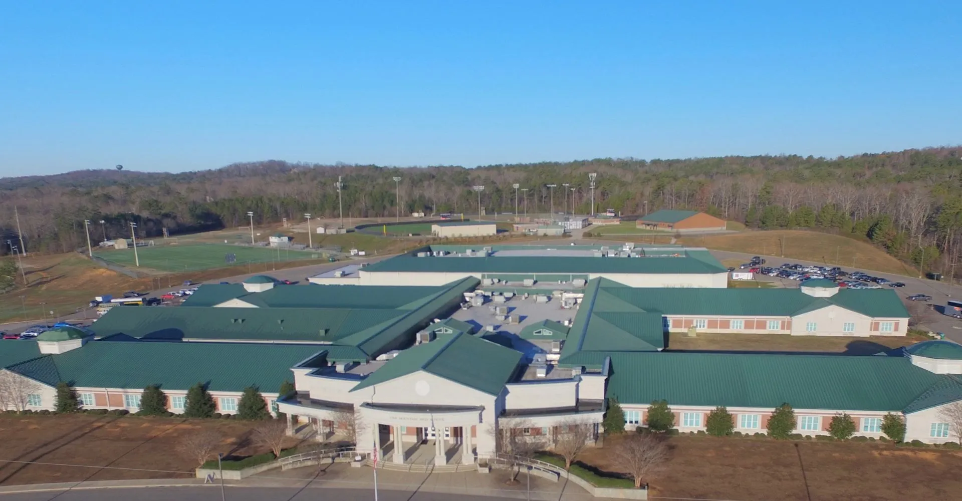 L'edificio principale della Oak Mountain Academy con tetto verde e impianti sportivi sullo sfondo di un paesaggio collinare.