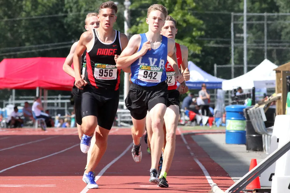 Due corritrici in abbigliamento sportivo durante una gara sulla pista di atletica della Nelson High School.