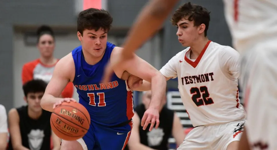 Due studenti della Westmount High School giocano a pallacanestro l'uno contro l'altro sul campo da gioco.