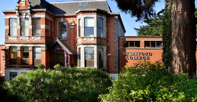 L'edificio storico in mattoni con dettagli architettonici decorativi nel campus del Stratford College è circondato da una verde vegetazione.