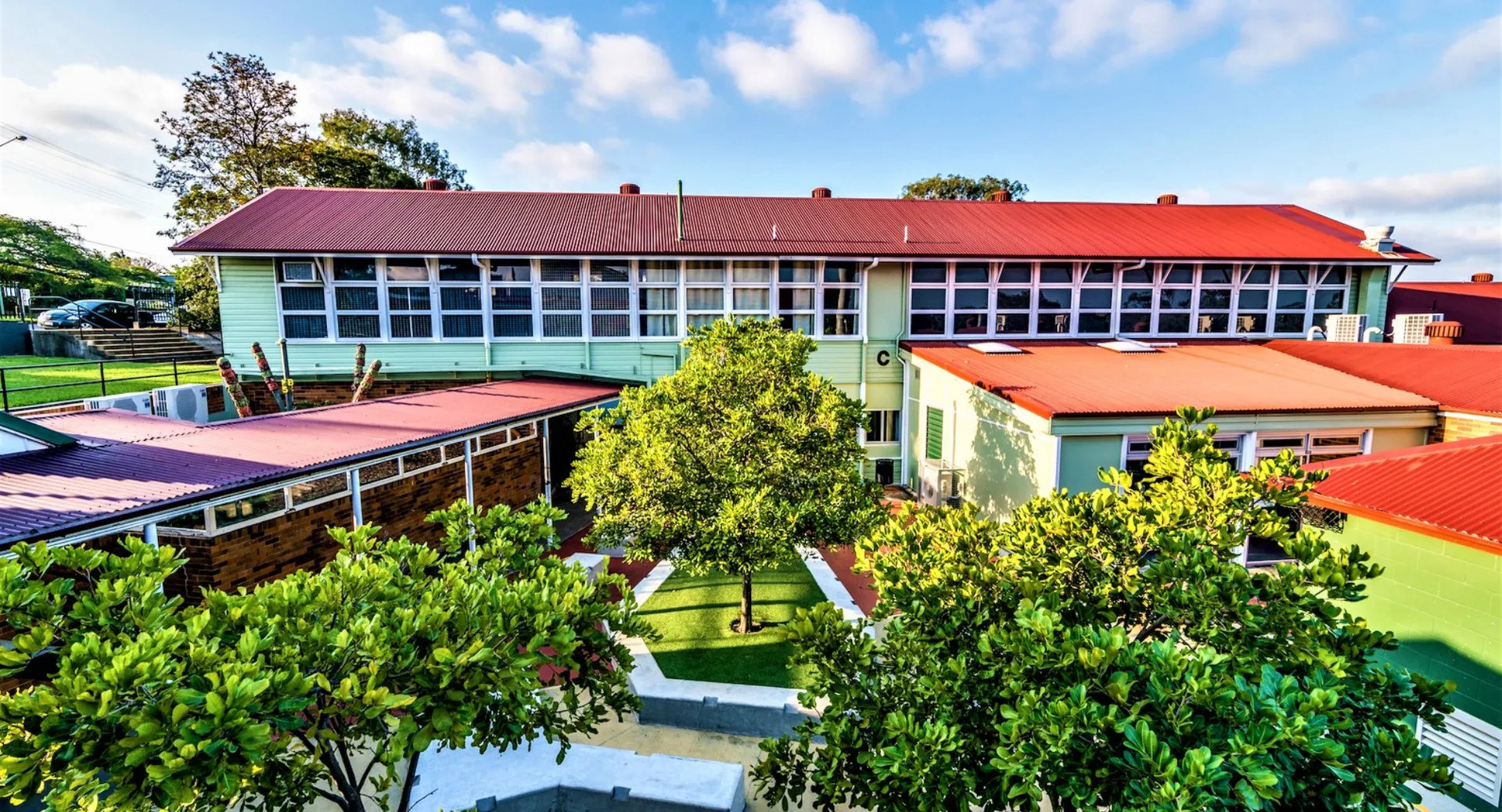 L'edificio colorato a più piani della Balmoral State High School è circondato da un giardino verde con un sentiero pavimentato.