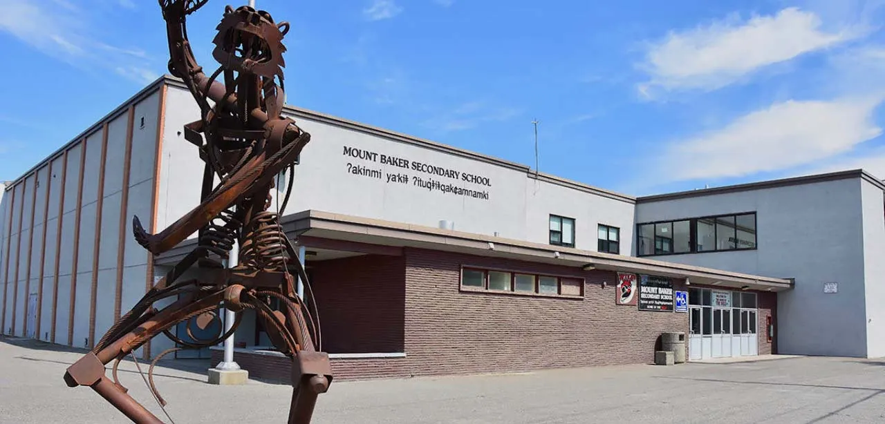 Una gran escultura de metal de una figura esquelética se encuentra frente al edificio moderno de la Mount Baker Secondary School.