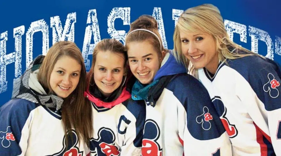 Quattro studentesse della Polyvalente Thomas-Albert indossano maglie sportive identiche e si trovano davanti a uno sfondo blu con la scritta Hockey.