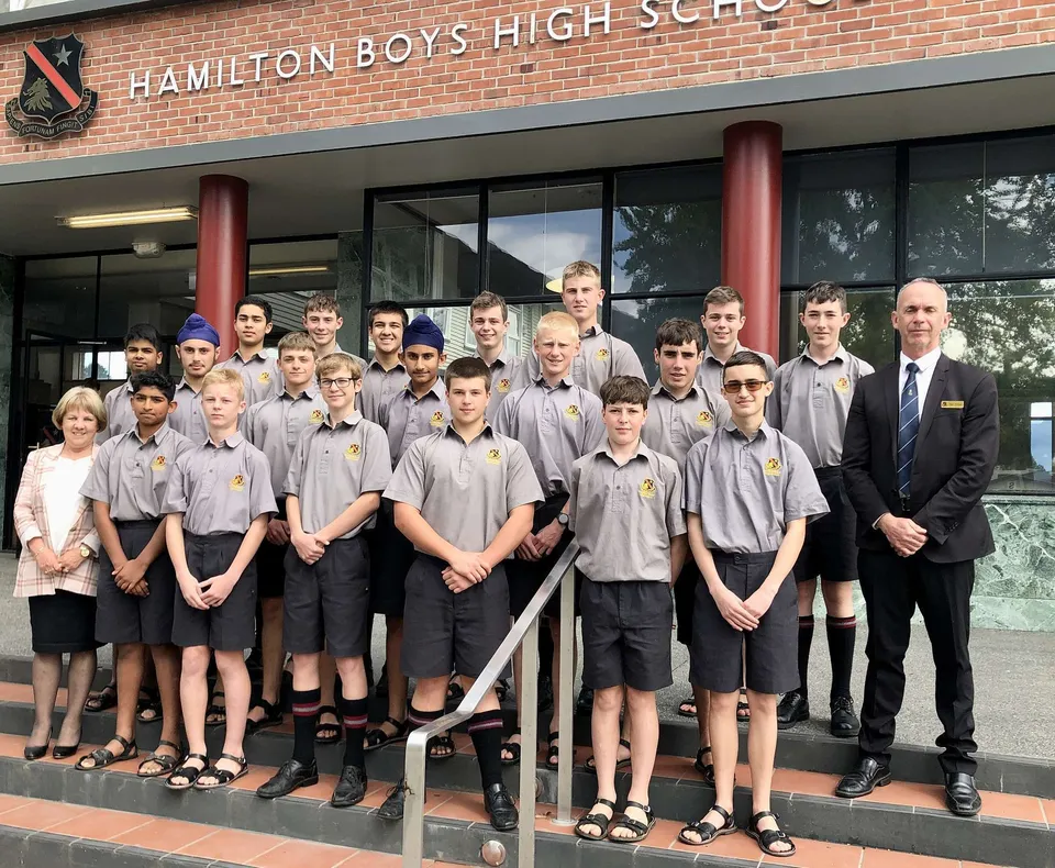 Un gruppo di studentesse, studenti e insegnanti posa davanti all'edificio scolastico della Hamilton Boy's High School.