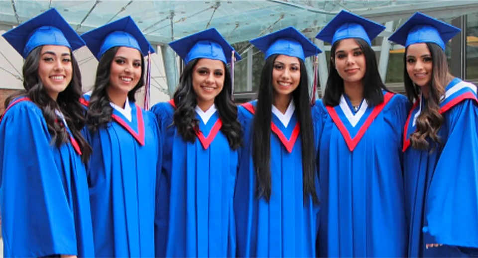 Un gruppo di studentesse della W.P. Wagner High School festeggia il diploma in toga e tocco blu.