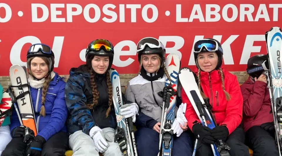 Studenti della Patrician Presentation Secondary School in attrezzatura da sci davanti al cartello Deposito Laborat Cheerkee.