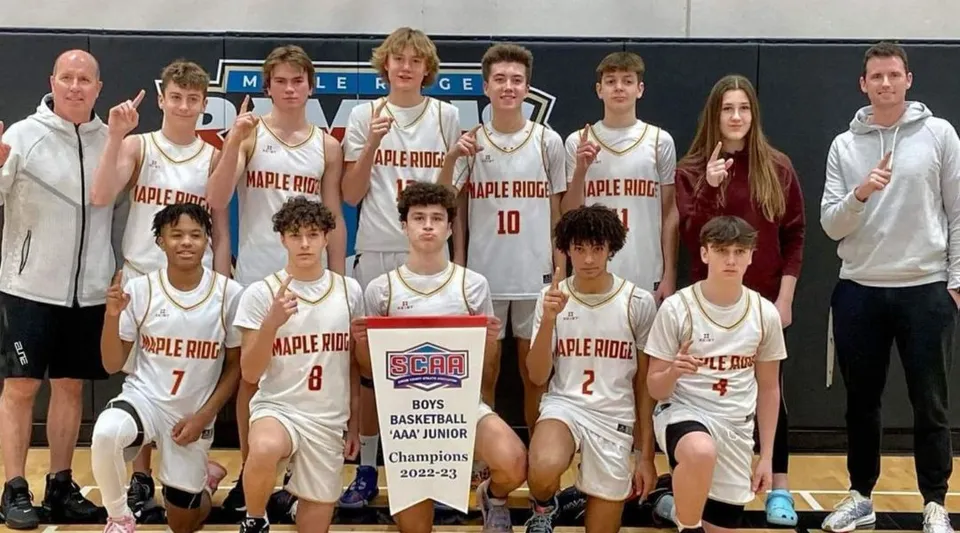 Un gruppo di giovani giocatori e giocatrici di basket posa davanti al logo Apple Ridge sul campus della Maple Ridge Secondary School in Ontario.