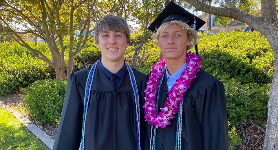 Due diplomati della Buena High School in toga nera da diploma posano all'aperto.