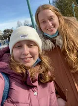 Zwei lächelnde junge Frauen in Winterjacken machen ein Selfie im Freien