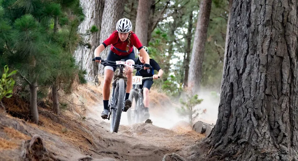 Uno studente della Lincoln High School va in bicicletta con una maglia rossa su un sentiero nel bosco.