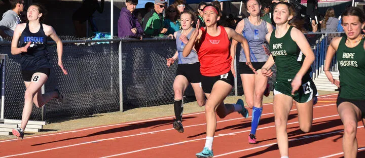 Corredoras de la Menaul School y otras escuelas compiten en una carrera de atletismo en la pista.