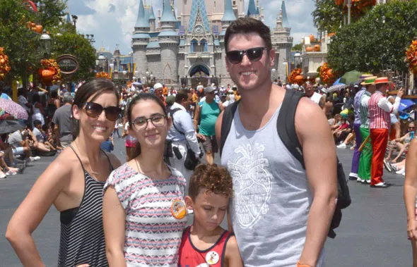 Una familia y una joven posan sonrientes en un parque temático frente a un castillo