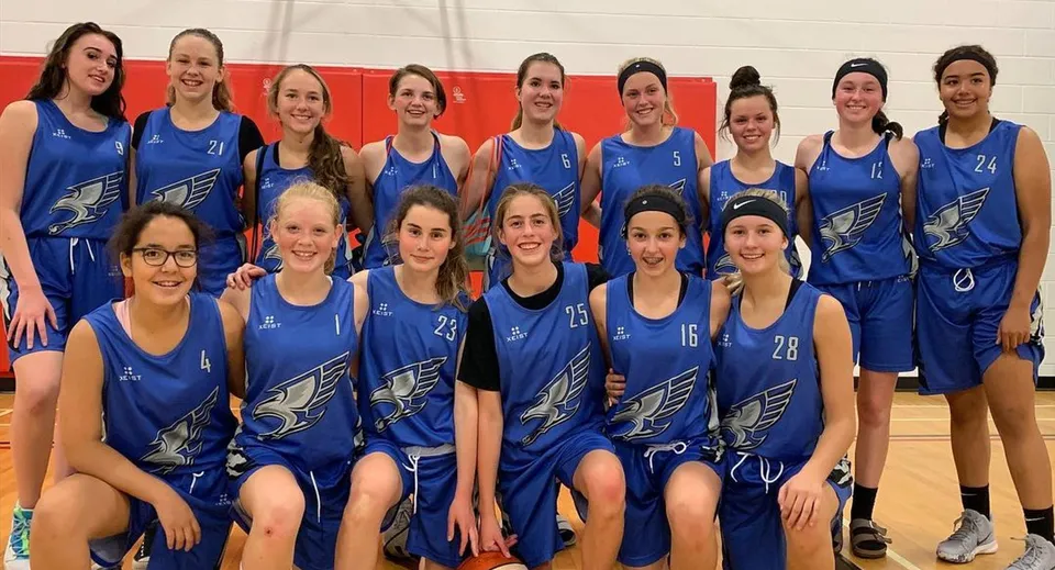 Un gruppo di studentesse della Innisdale Secondary School in divisa blu posa insieme in una palestra.