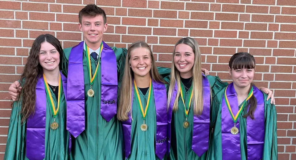 Neodiplomati della Centennial Secondary School in Ontario indossano le tradizionali toghe davanti a un muro di mattoni.