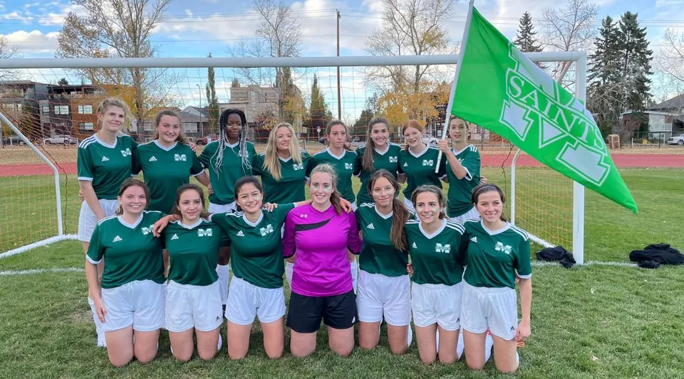 Un gruppo di giovani calciatrici è insieme sul campo da calcio della St. Mary's High School.