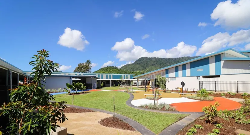 L'edificio scolastico moderno e colorato della Malanda State High School con un'area esterna ben curata e un paesaggio montano sullo sfondo.