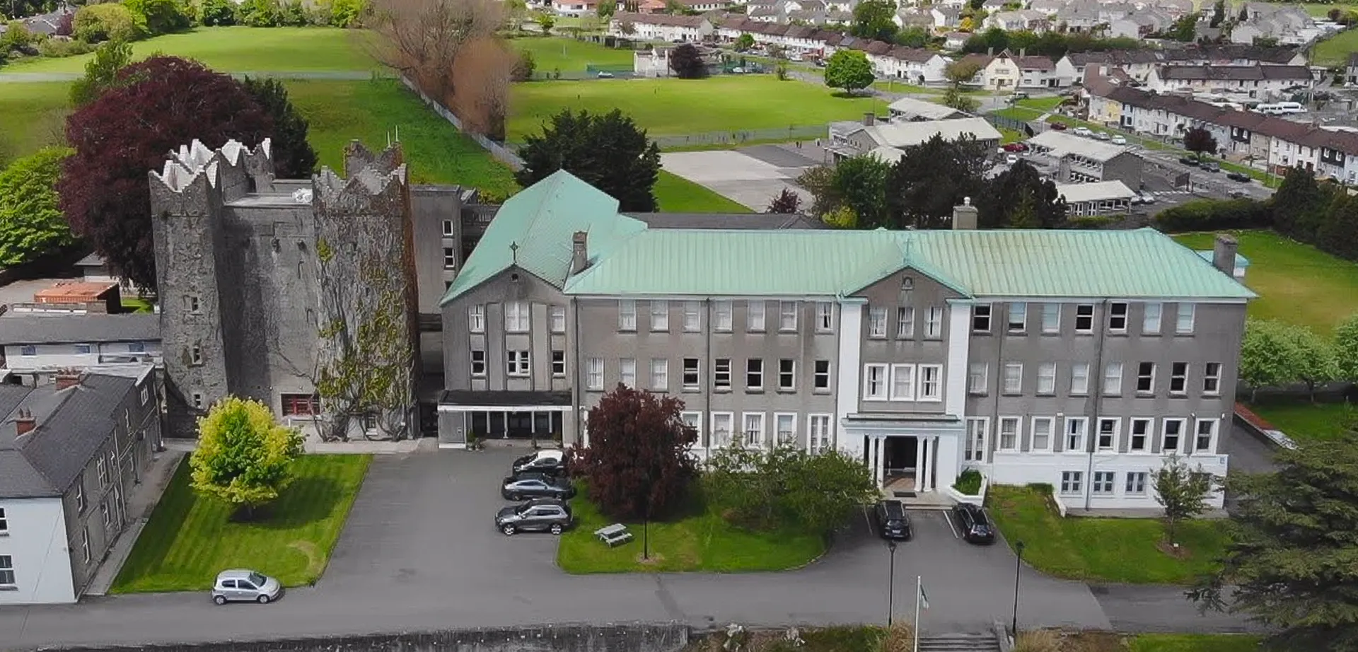 Vista esterna della St. Louis Secondary School a Dundalk con edifici storici e moderni oltre a un curato spazio verde in primo piano.