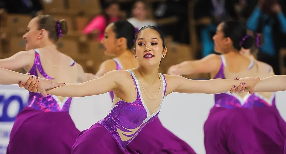 Un gruppo di ballerine della Winchendon School New York City si esibisce in uno spettacolo di danza su un palco indossando costumi viola.