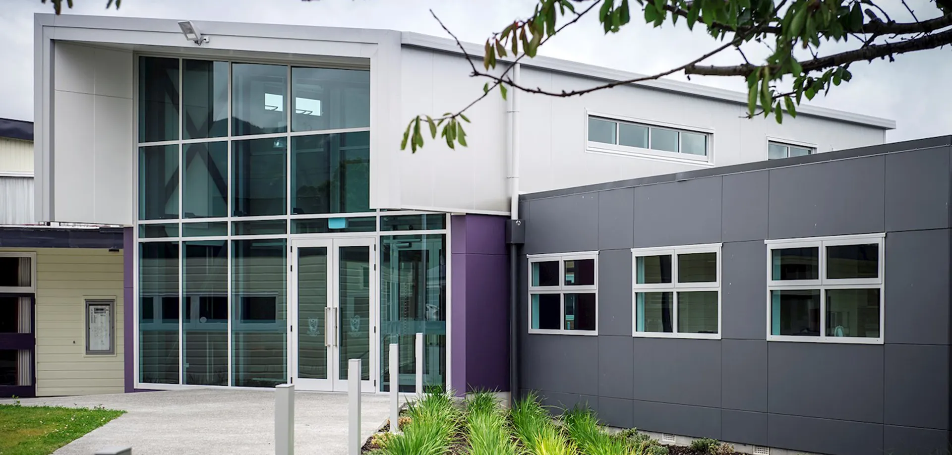 L'edificio principale del Heretaunga College, moderno e a più piani, con pareti in vetro e dettagli viola, è circondato da alberi.