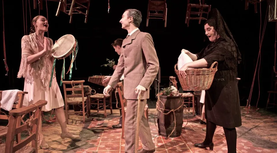 Tre persone si trovano all'interno di una scenografia teatrale nel campus della Tring Park School for the Performing Arts.