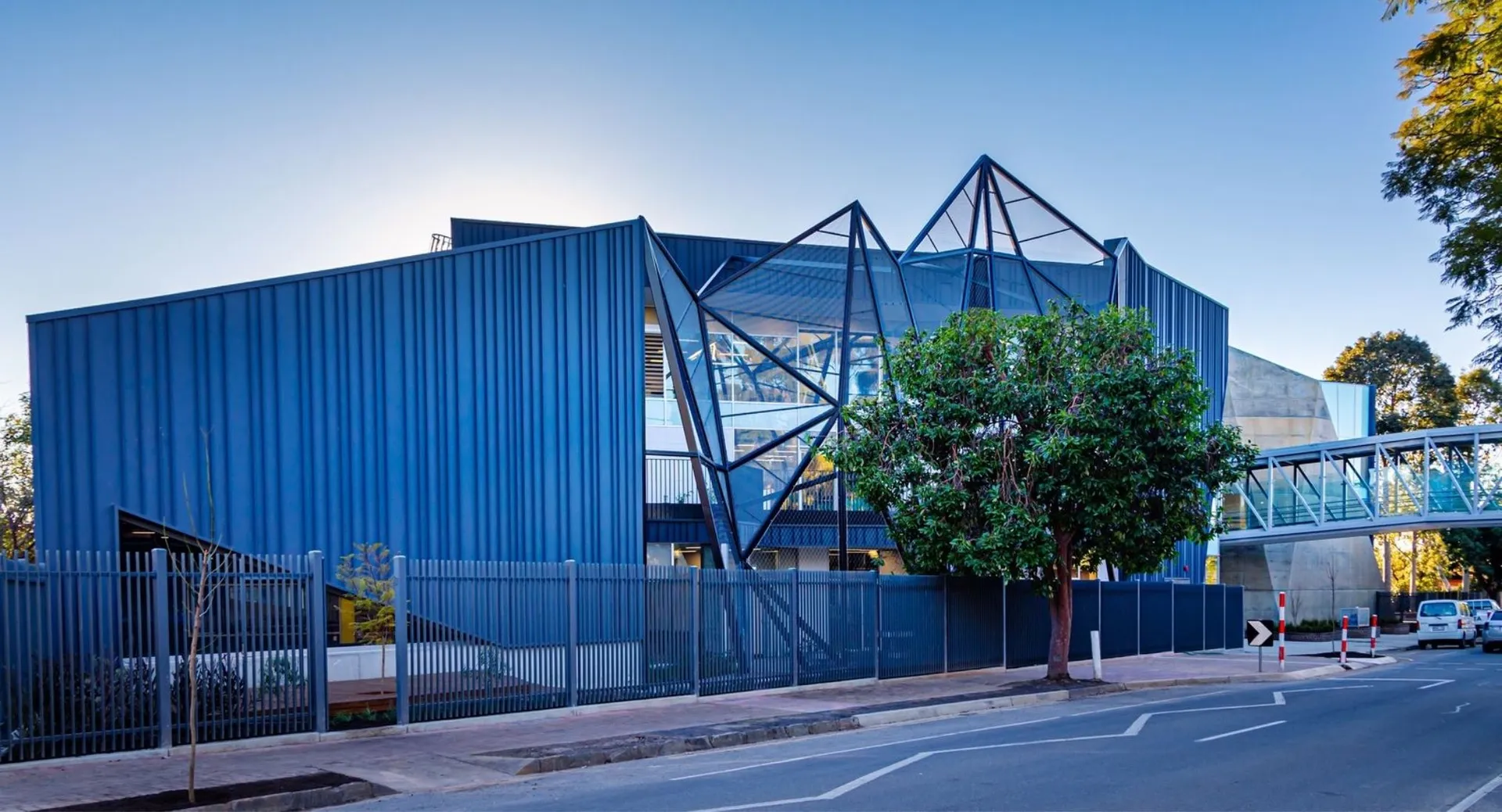 L'edificio moderno della Pembroke School con finestre triangolari di vetro blu si trova dietro una recinzione metallica.