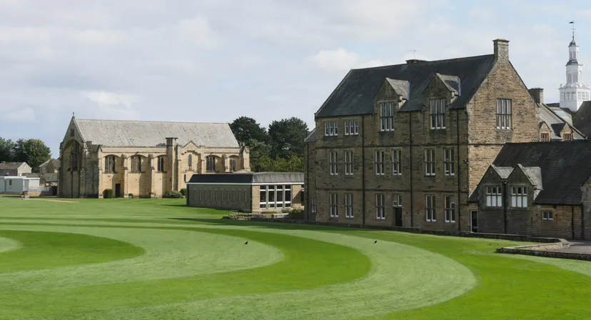 Gli edifici storici in pietra della Barnard Castle School con un ampio prato verde.