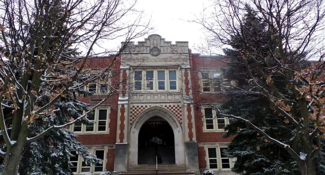 Das historische Hauptgebäude des Guelph Collegiate Vocational Institute steht im verschneiten Wald.