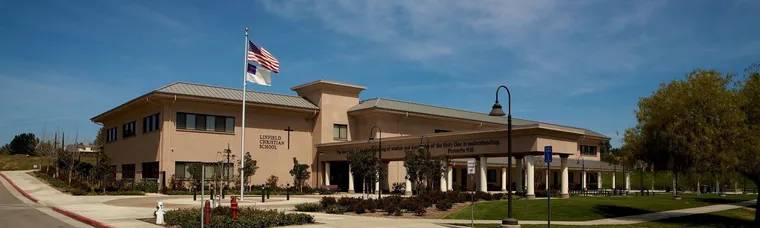 Flaches Schulgebäude mit US-Flagge am Fahnenmast unter blauem Himmel