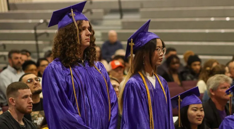 Un gruppo di diplomati in toga viola si trova nell'aula magna delle Overland Christian Schools.