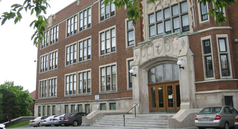 L'edificio in mattoni a più piani del Glebe Collegiate Institute è circondato da alberi e auto parcheggiate.