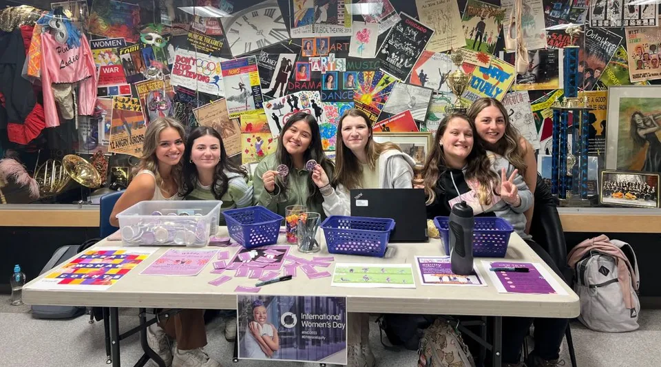 Studentesse della St. Francis High School riunite attorno a un tavolo con prodotti colorati e poster nell'area vendita.