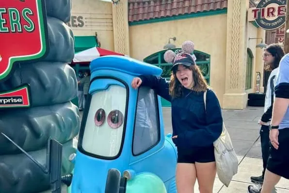 Chica con gorra de orejas posa junto a la estatua azul de Cars