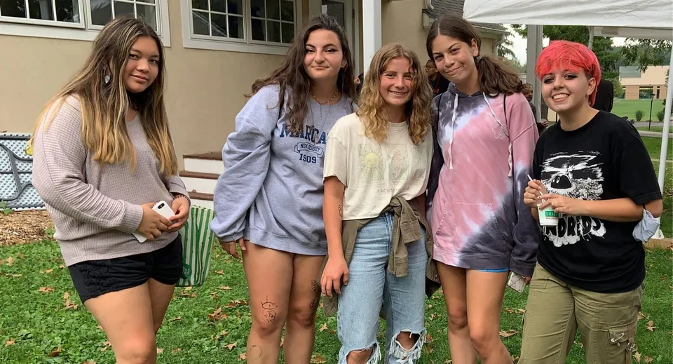Un gruppo di cinque studentesse è insieme davanti a un edificio del campus della Solebury School.