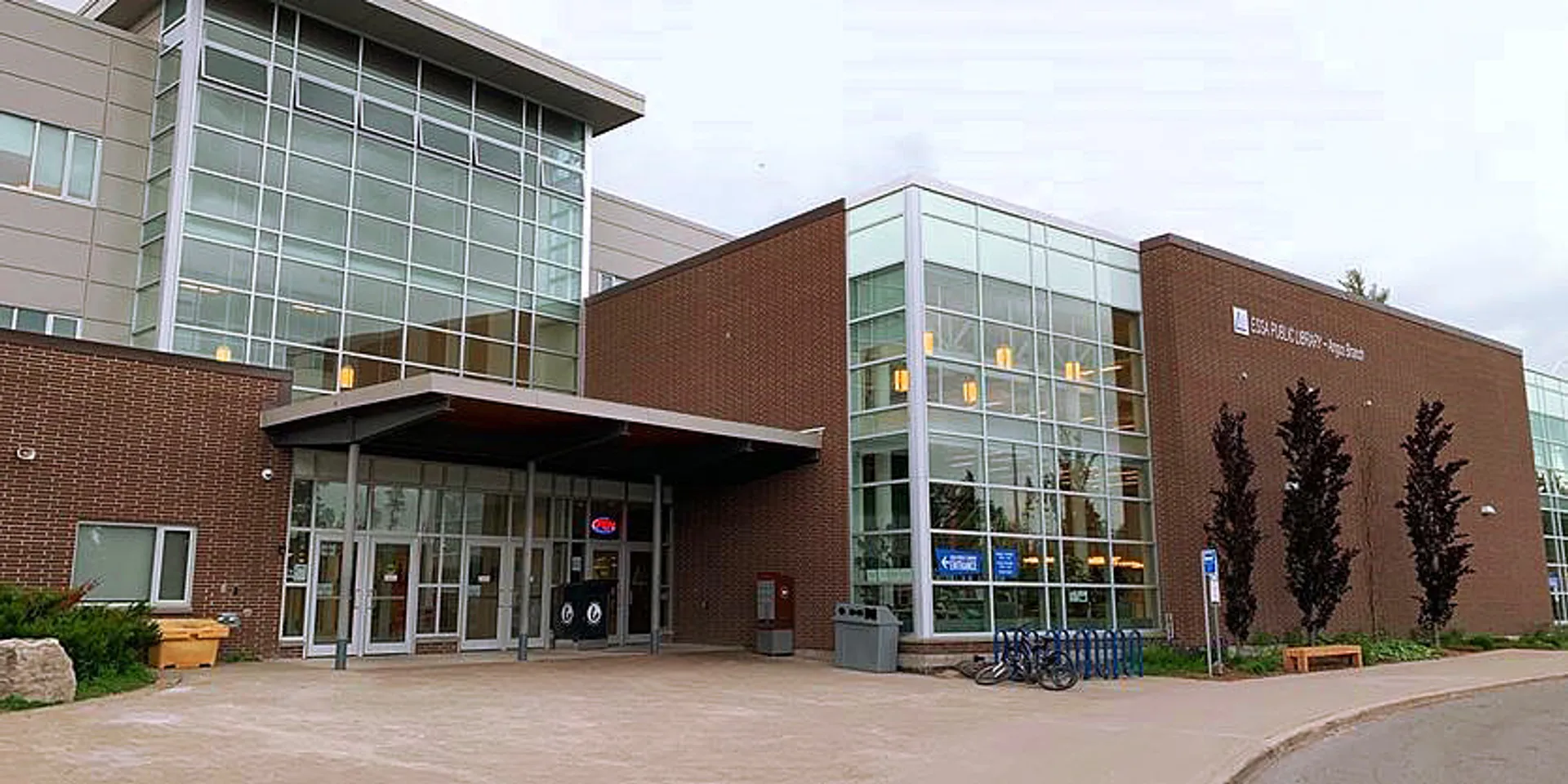 L'edificio moderno a più piani della Nottawasaga Pines Secondary School, con facciata in vetro e parete esterna in mattoni, sorge lungo un vialetto pavimentato.
