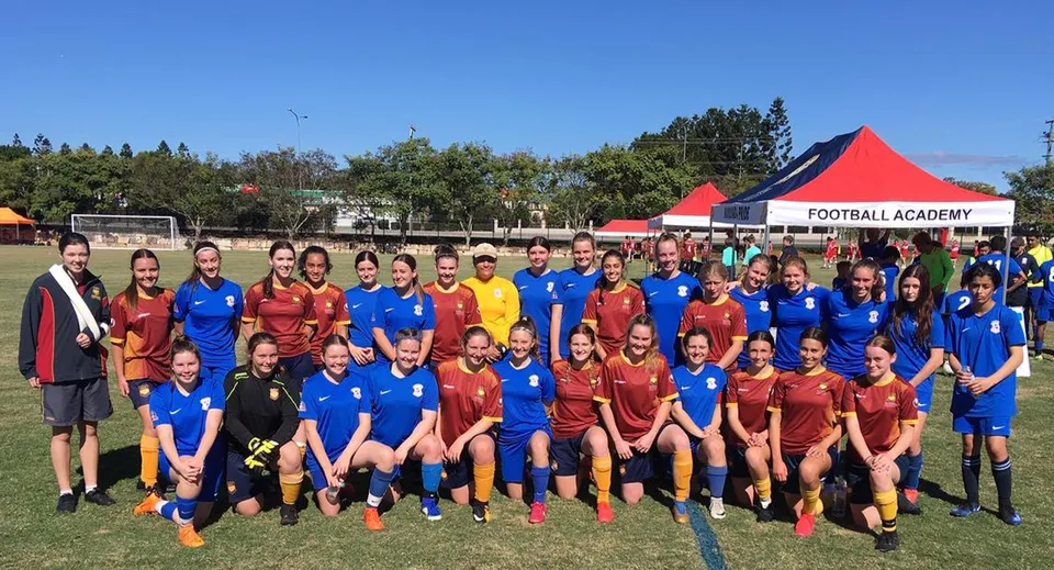 Un gruppo di giovani calciatrici posa sul campo da calcio del Murrumba State Secondary College davanti a una tenda della Football Academy.