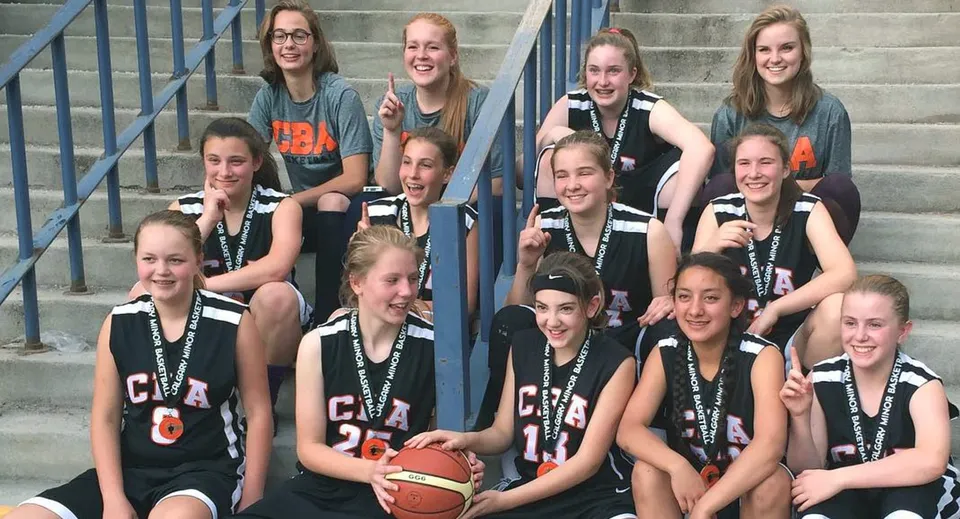 Un gruppo di giovani studentesse posa con le divise da basket su una scalinata della James Fowler High School.
