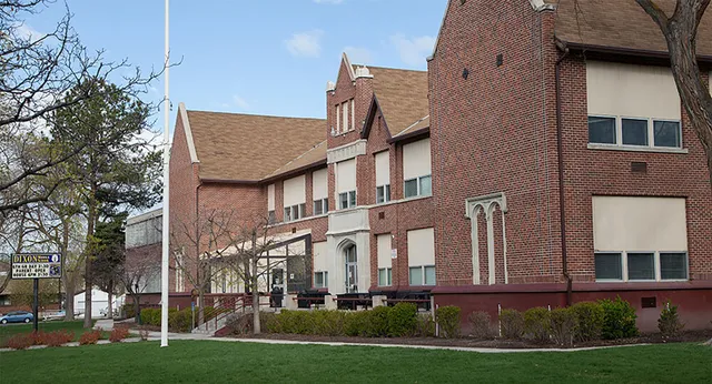 Das Backsteingebäude mit markanter Architektur auf dem Campus des Provo City School District ist von einer Grünfläche und Bäumen umgeben.