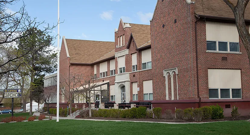 L'edificio in mattoni con un'architettura caratteristica nel campus del Provo City School District è circondato da un'area verde e alberi.
